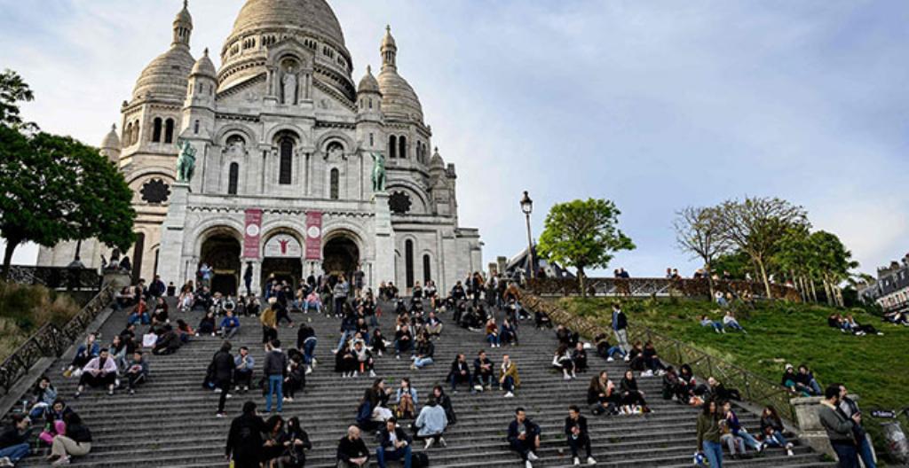 Människor sitter på trapporna vid kyrkan Sacré-Coeur i Frankrikes huvudstad Paris.
