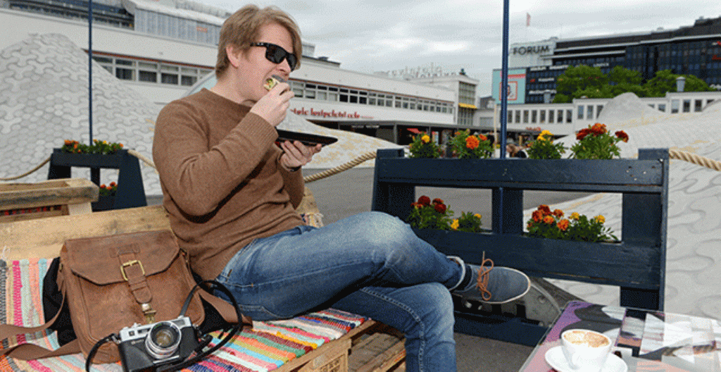 En man åt frukost den första juni på en uteservering vid Glaspalatset i centrum av Helsingfors. 