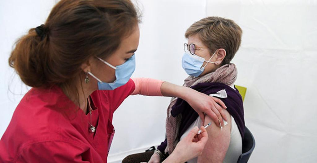 En sjuksköterska ger vaccin i armen.