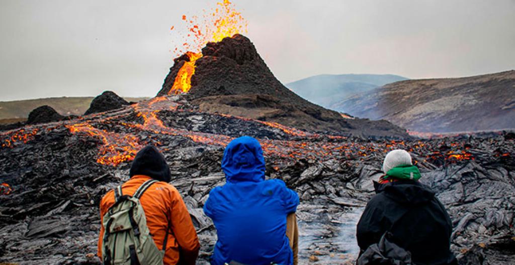Några vandrare tittar på vulkanutbrottet på Island.