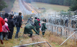 Människor står vid ett staket gjort av taggtråd.