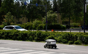En liten vit robot kör längs en gata.