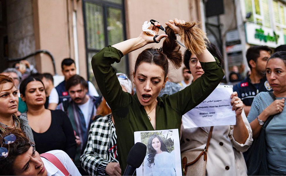 En iransk kvinna som bor i Turkiet, klipper av sitt hår under en protest.