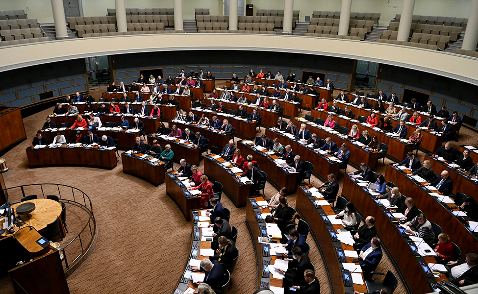 Bilden visar riksdagens plenisal i Helsingfors. En plenisal är ett jättestort rum där alla ledamöter i riksdagen ryms in för att diskutera och ta beslut.