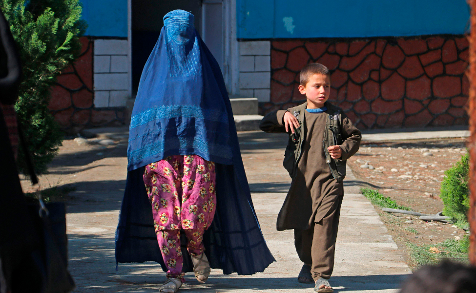 Bilden visar en afghansk kvinna som promenerar tillsammans med en pojke i Afghanistan.