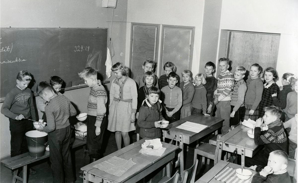 Elever i folkskolan Rajamäen koulu i Nurmijäri köar för att få skolmat. Bilden är tagen på 1950- eller 1960-talet. 