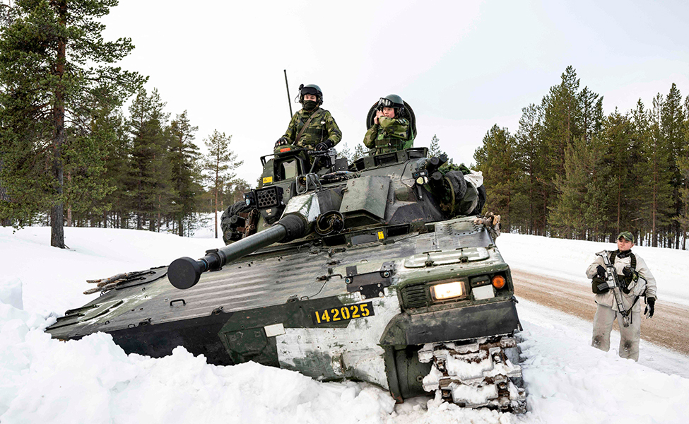Soldater och en pansarvagn i snöig terräng. 