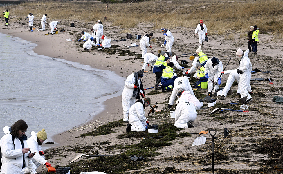 folk i skyddsdräkter på strand