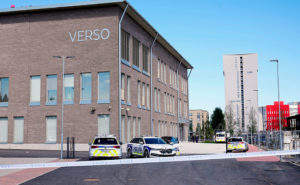 En bild av en skolbygnad. Runt omkring skolan står flera polisbilar.